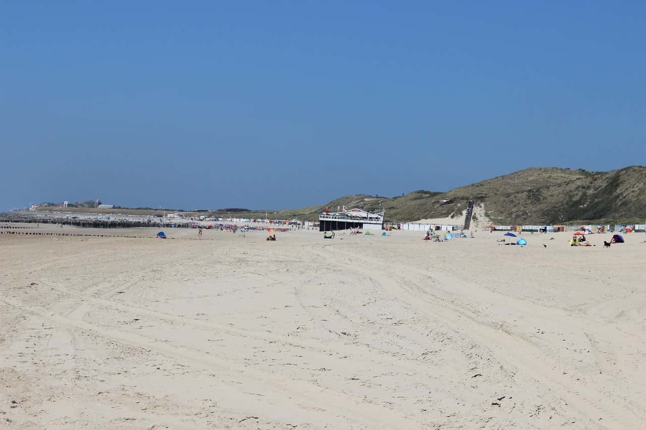 Breiter Sandstrand mit Badegästen und Dünen